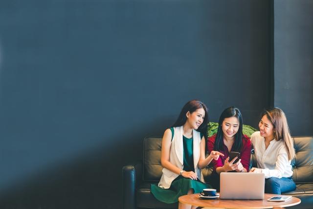 Three Asian girls using smartphone and laptop, chattin