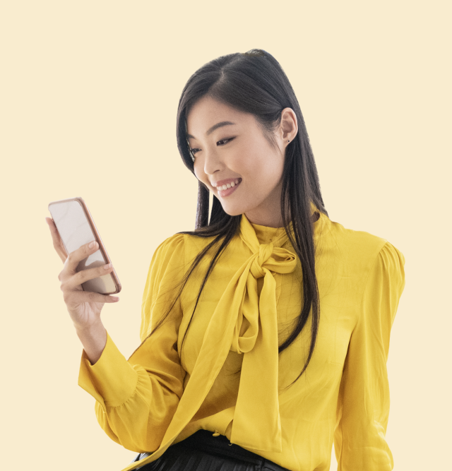 Asian woman looking at phone yellow background